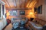 Step into a cozy retreat with this charming living space, featuring warm wooden paneling and exposed beams that create a rustic ambiance.