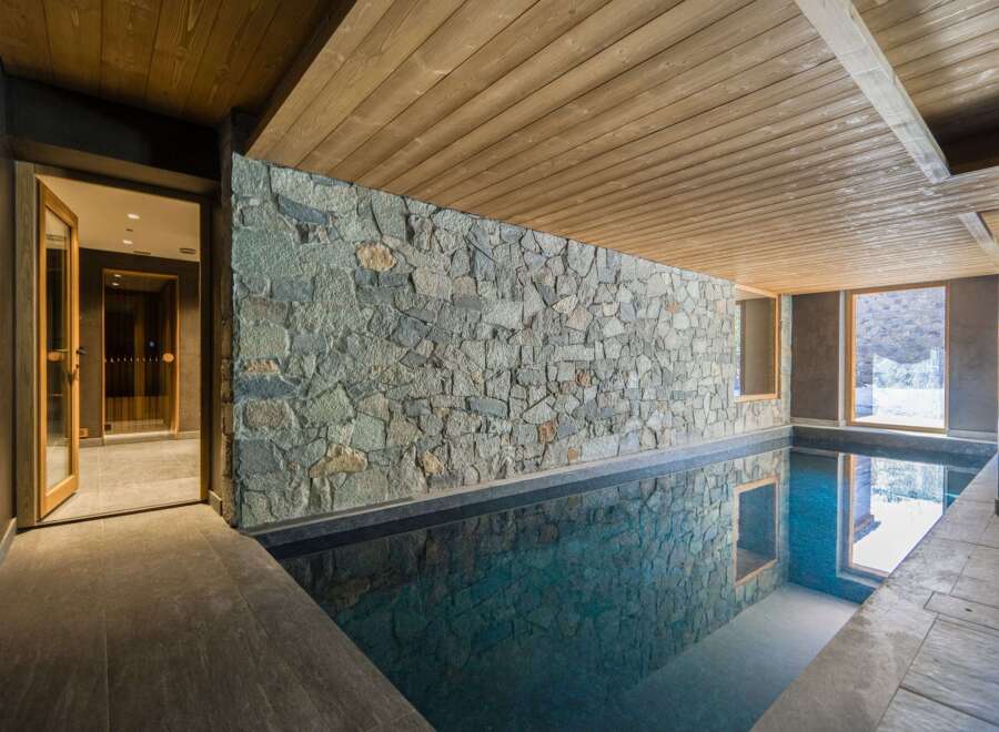 This stunning indoor pool features a beautiful stone wall and wooden ceiling, creating a luxurious and relaxing atmosphere.