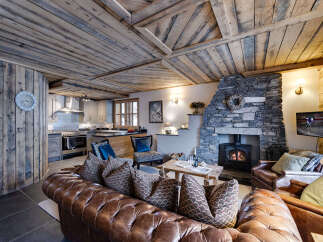 Experience rustic elegance in this stunning property, featuring a cozy living room with a stone fireplace and exposed wooden beams.