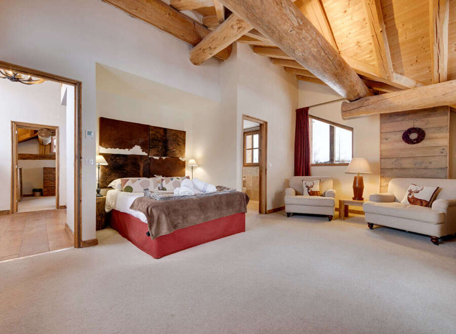 This luxurious bedroom boasts a rustic charm with its exposed wooden beams and cowhide headboard.