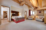 This luxurious bedroom boasts a rustic charm with its exposed wooden beams and cowhide headboard.