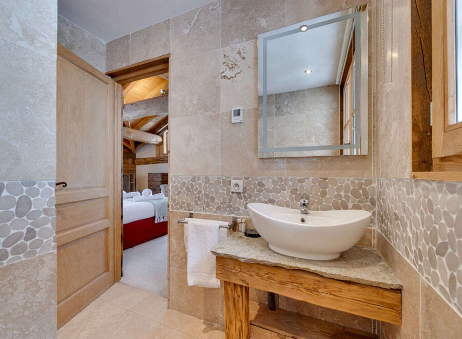 This stunning bathroom features a unique stone sink and a stylish mirror, creating a luxurious and inviting space.