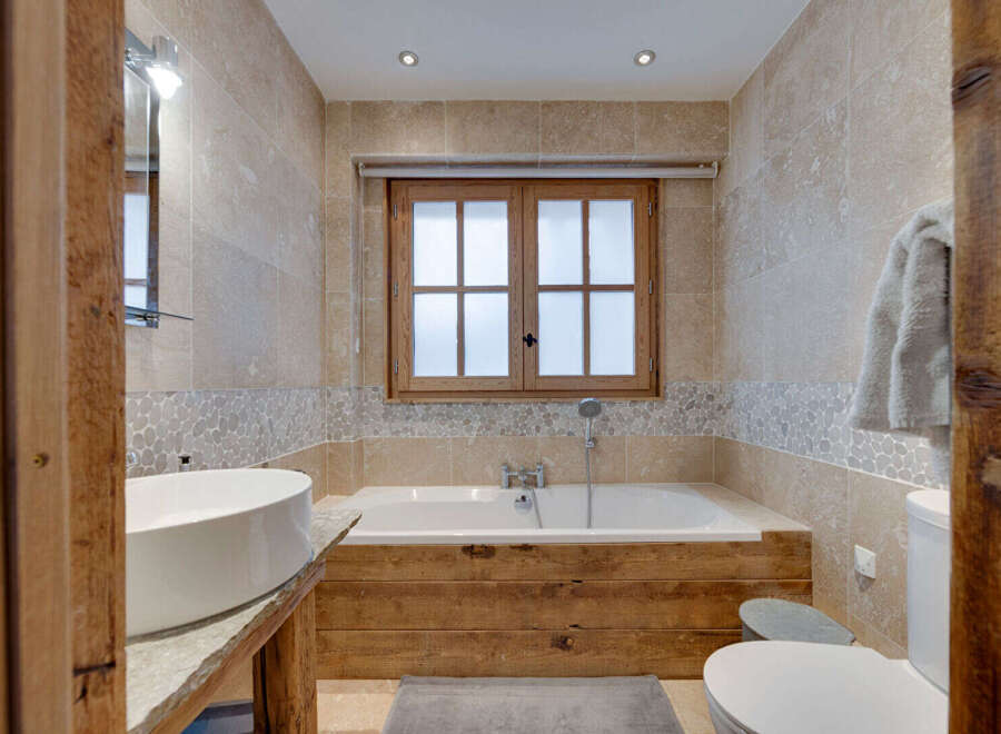 This luxurious bathroom features a stunning wooden bathtub surround, creating a warm and inviting atmosphere.
