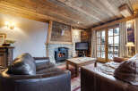 Experience the warmth of this charming chalet, featuring a cozy living room with a stone fireplace and exposed wooden beams.