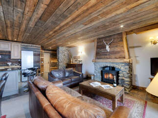 Experience rustic charm in this stunning living space, featuring a cozy fireplace and exposed wooden beams.