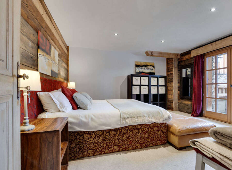 This luxurious bedroom showcases rustic charm with its wooden accent walls and elegant decor.