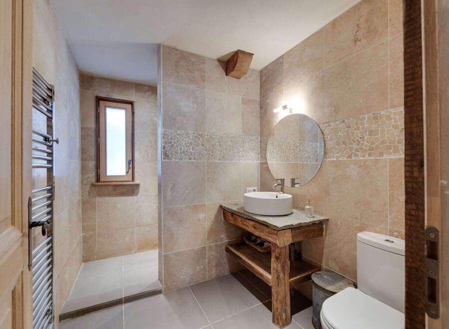 This stunning bathroom boasts a rustic charm with its stone-tiled walls and wooden accents.
