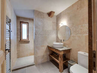 This stunning bathroom boasts a rustic charm with its stone-tiled walls and wooden accents.