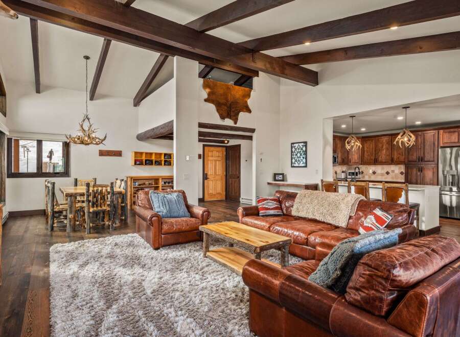 Step into luxury with this stunning property, featuring a spacious living area with exposed wooden beams and a cozy fireplace.