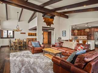 Step into luxury with this stunning property, featuring a spacious living area with exposed wooden beams and a cozy fireplace.