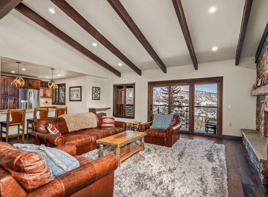 Step into luxury with this stunning living space, boasting a cozy leather sofa and a plush rug, perfect for relaxing after a day on the slopes.