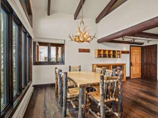 Step into rustic elegance with this stunning dining room! Featuring a unique antler chandelier, a custom wooden dining table, and log-style chairs, this space exudes warmth and charm.