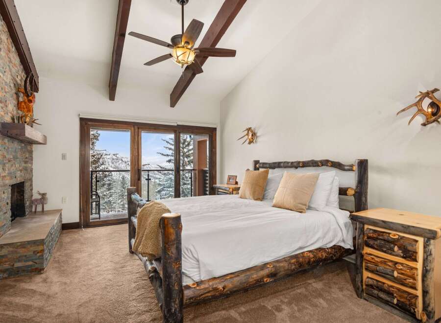 This stunning bedroom boasts rustic charm with its log-style bed frame and cozy fireplace.