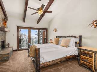 This stunning bedroom boasts rustic charm with its log-style bed frame and cozy fireplace.