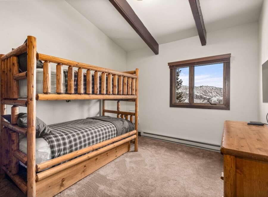 This cozy bedroom features a rustic log bunk bed, perfect for a mountain getaway.