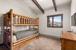 This cozy bedroom features a rustic log bunk bed, perfect for a mountain getaway.