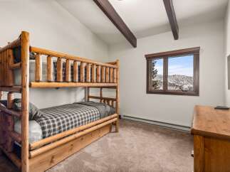 This cozy bedroom features a rustic log bunk bed, perfect for a mountain getaway.