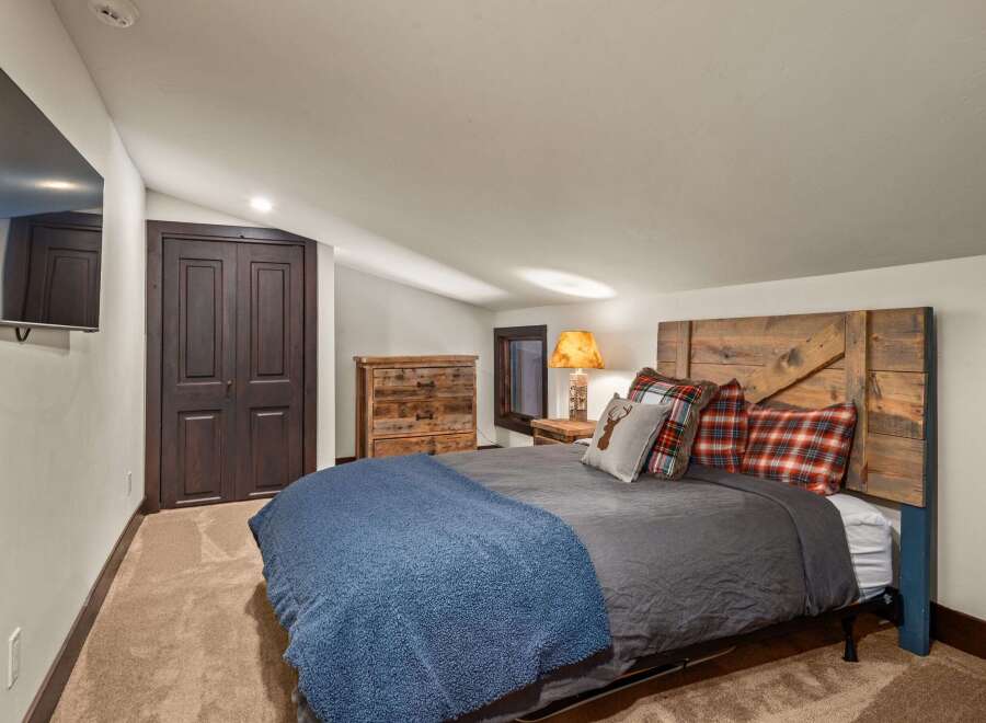 This cozy bedroom features a rustic wooden headboard and a plush blue blanket, creating a warm and inviting atmosphere.