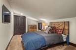 This cozy bedroom features a rustic wooden headboard and a plush blue blanket, creating a warm and inviting atmosphere.