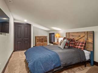 This cozy bedroom features a rustic wooden headboard and a plush blue blanket, creating a warm and inviting atmosphere.