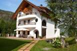 This stunning property boasts a charming architectural design with a white exterior and a warm wooden roof.