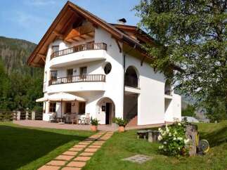 This stunning property boasts a charming architectural design with a white exterior and a warm wooden roof.