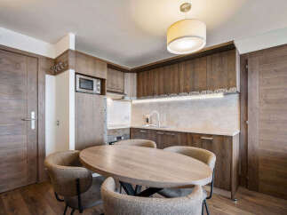 This stunning property boasts a modern kitchen with sleek wooden cabinetry and a cozy dining area.