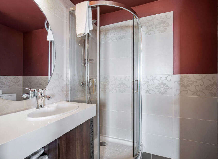 Step into a modern bathroom oasis! This stylish space features a sleek sink, a glass-enclosed shower, and elegant tilework.