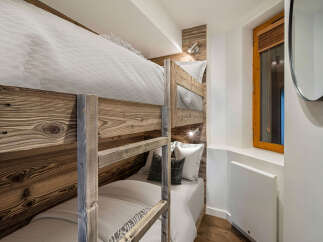 This cozy bedroom features custom-built bunk beds with rustic wooden frames, perfect for maximizing space.