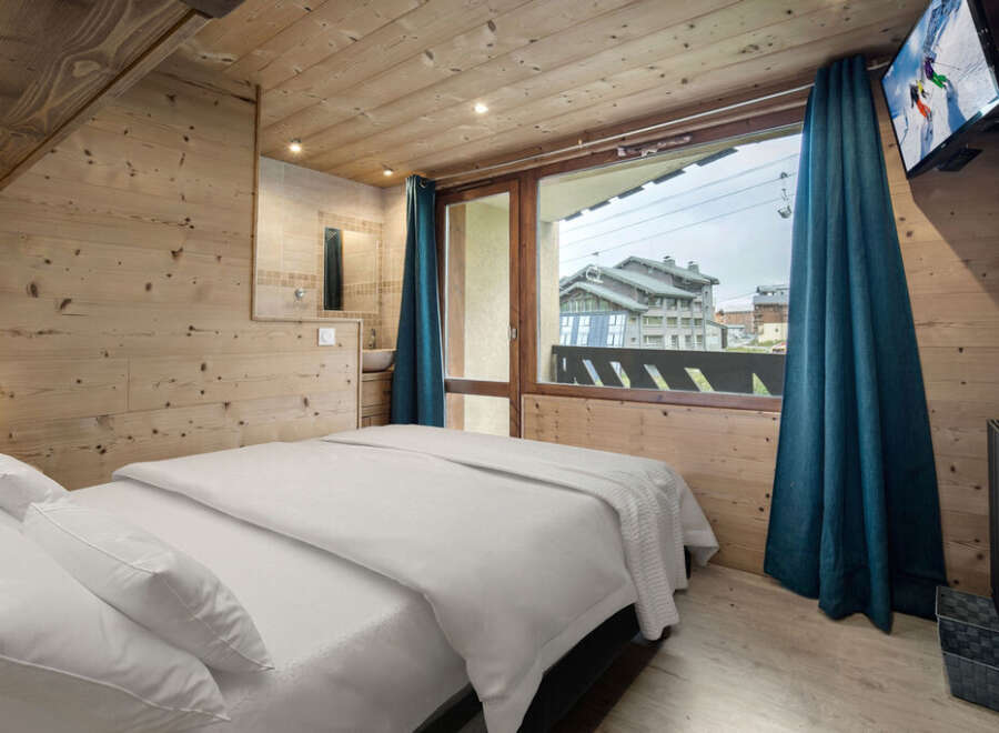 Experience the charm of this cozy bedroom, featuring warm wooden accents and a comfortable bed.