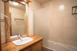 This charming bathroom features a wooden vanity with a sleek white sink, offering a touch of rustic elegance.