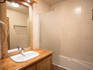 This charming bathroom features a wooden vanity with a sleek white sink, offering a touch of rustic elegance.