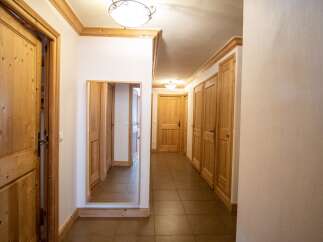 Step into this inviting hallway, featuring warm wooden doors and trim that exude a cozy ambiance.