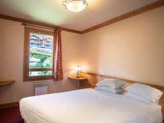 This cozy bedroom features a comfortable bed with crisp white linens, perfect for a relaxing stay.