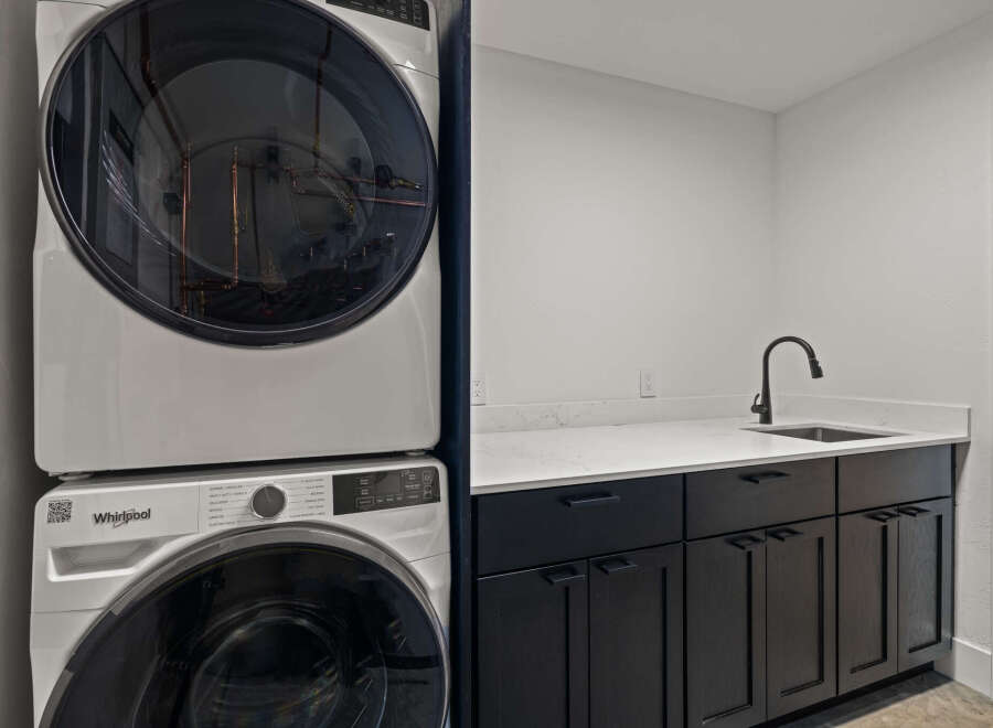 This modern laundry room features a sleek design with a stacked Whirlpool washer and dryer, offering both style and functionality.