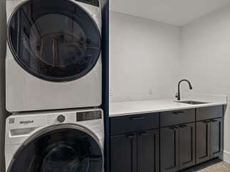 This modern laundry room features a sleek design with a stacked Whirlpool washer and dryer, offering both style and functionality.