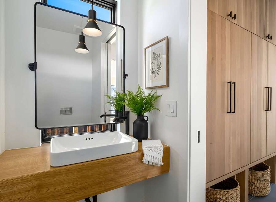 This modern bathroom features a sleek, minimalist design with a floating wooden vanity and a rectangular sink.
