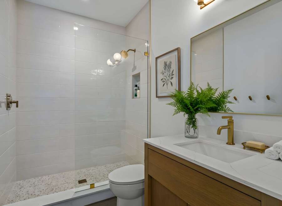 Step into a luxurious bathroom retreat! This stunning space features a modern shower with sleek glass doors and elegant gold accents.
