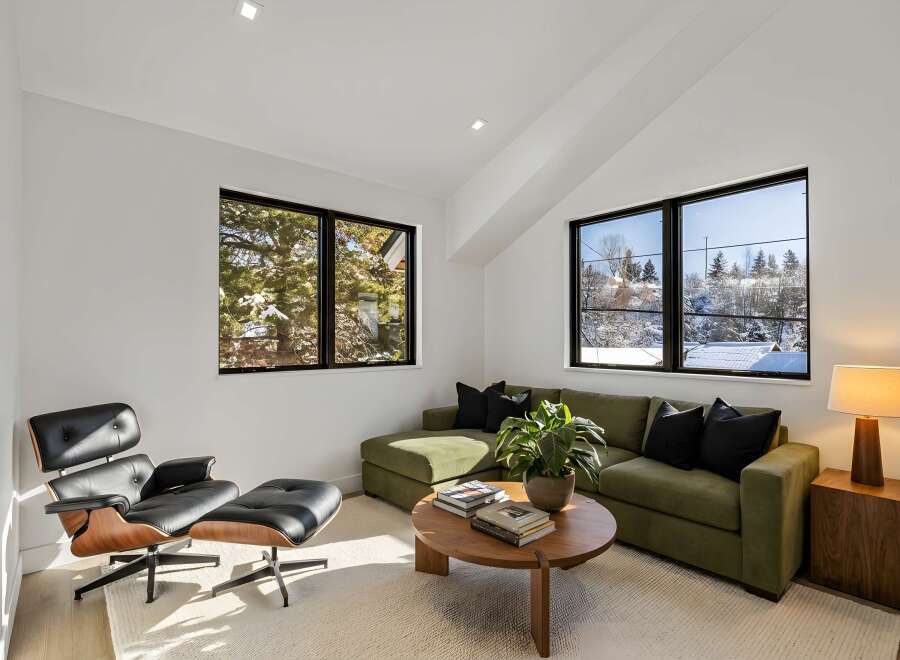 This stunning living room boasts a modern design with a comfortable green sectional sofa and a stylish Eames lounge chair.