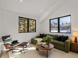 This stunning living room boasts a modern design with a comfortable green sectional sofa and a stylish Eames lounge chair.