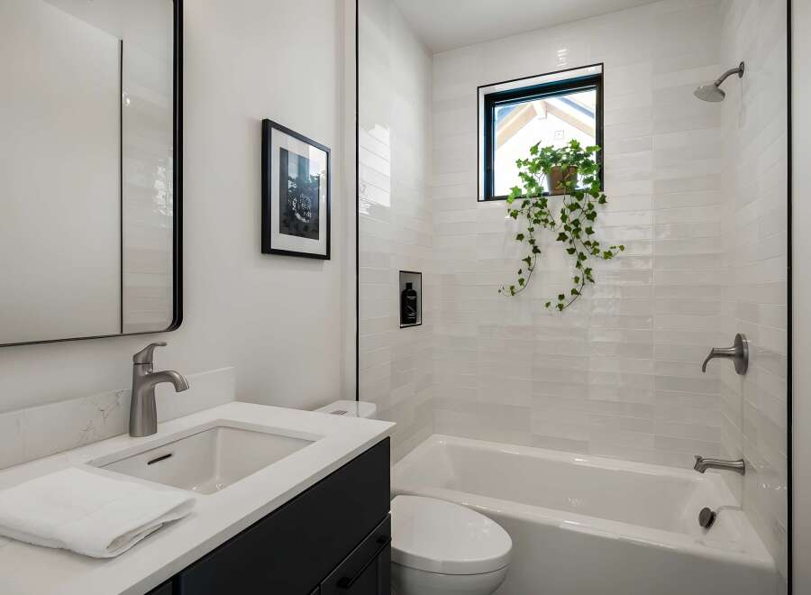 This modern bathroom features a sleek design with a white color scheme and a touch of nature.
