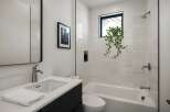 This modern bathroom features a sleek design with a white color scheme and a touch of nature.