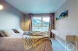 Experience the epitome of comfort in this stunning bedroom, featuring a cozy bed adorned with plush pillows and a luxurious throw.