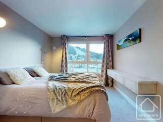 Experience the epitome of comfort in this stunning bedroom, featuring a cozy bed adorned with plush pillows and a luxurious throw.