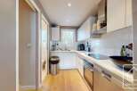 Discover this modern kitchen, featuring sleek white cabinetry and countertops, perfect for culinary enthusiasts.