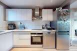 This modern kitchen boasts sleek white cabinetry, stainless steel appliances, and a minimalist design.