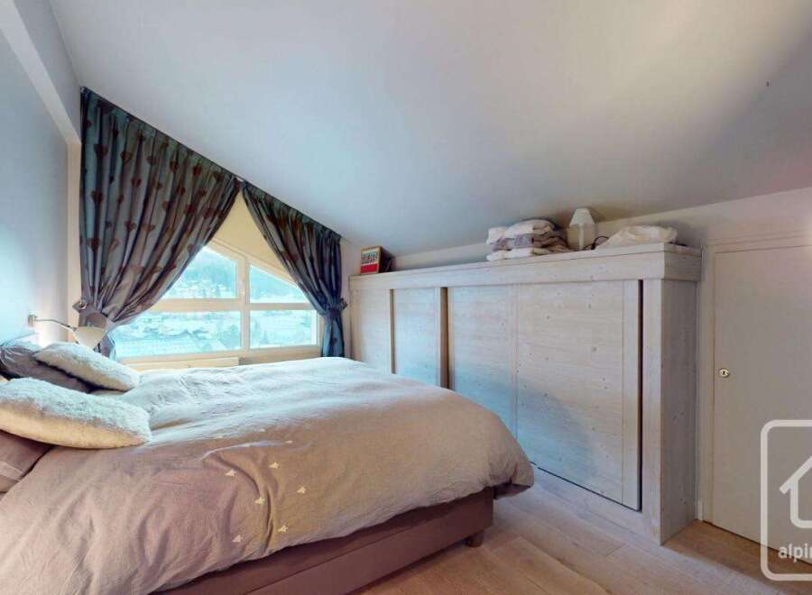 Discover the charm of this cozy bedroom, featuring a comfortable bed and a unique window design.