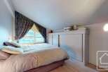 Discover the charm of this cozy bedroom, featuring a comfortable bed and a unique window design.