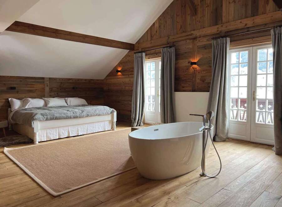 Experience luxury in this stunning bedroom featuring a freestanding bathtub and a cozy bed.