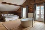 Experience luxury in this stunning bedroom featuring a freestanding bathtub and a cozy bed.